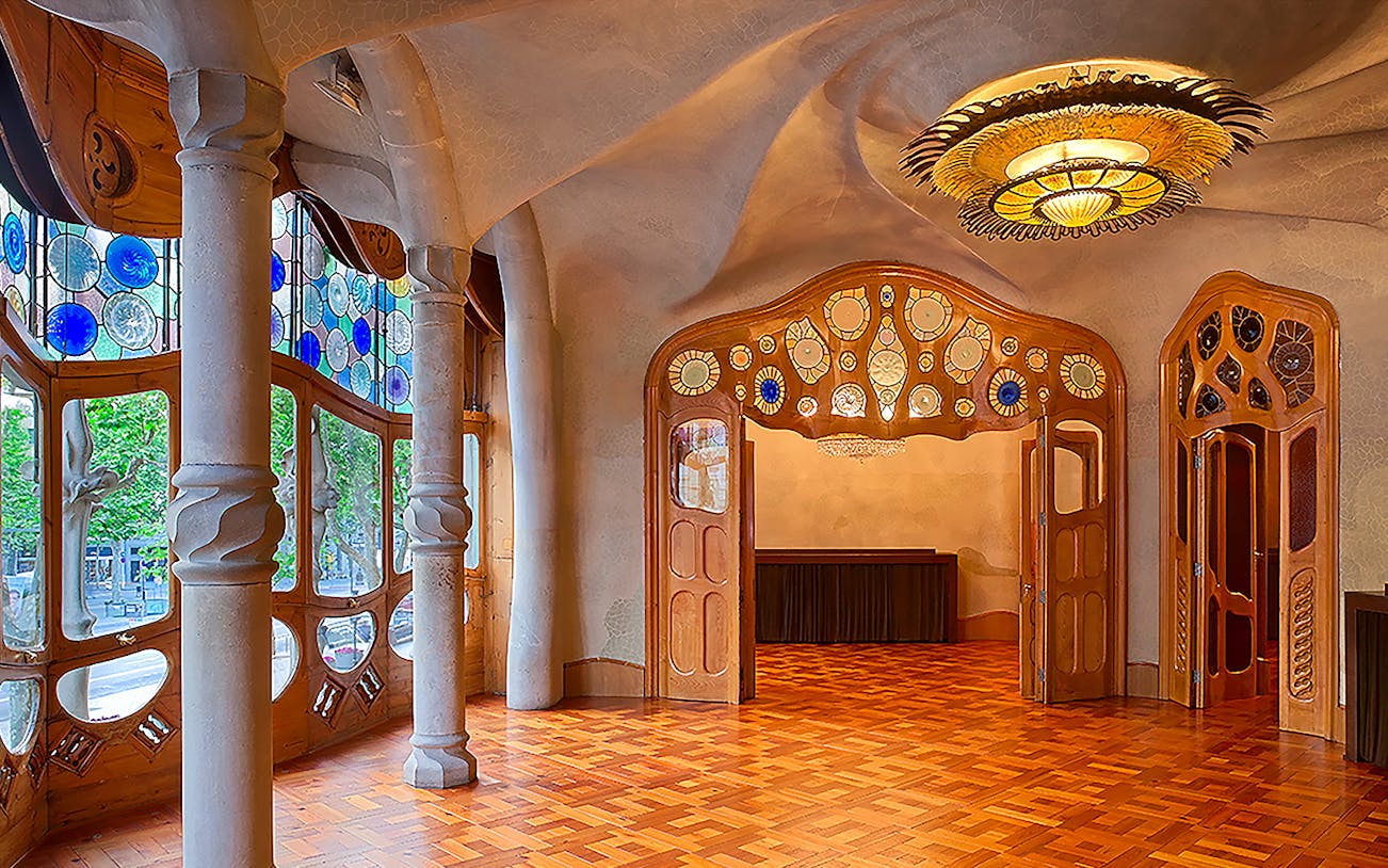 Casa Batlló interior with stained glass windows and ornate ceiling in Barcelona.