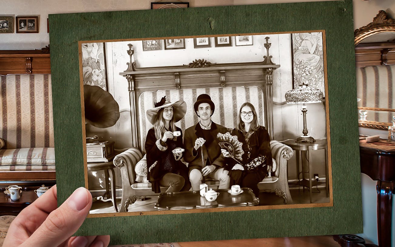 Three people in vintage attire posing with tea set at Casa Batlló, Barcelona.