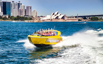 Jet boat speeding in Sydney Harbour with the Opera House in the background.