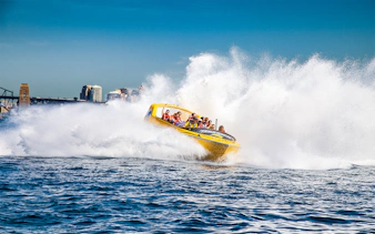 Jet boat speeding through water near Sydney Harbour Bridge, Thunder Thrill Ride.