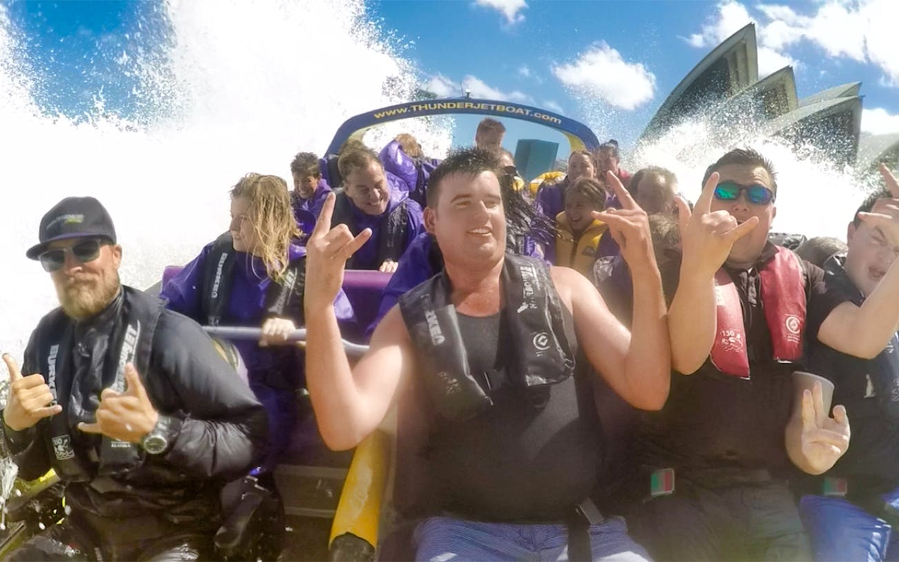 Group enjoying Thunder Thrill Ride on a jet boat with water splashing, Sydney Opera House in background.