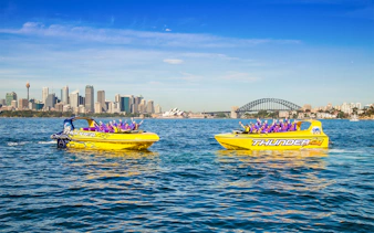 Jet boats on Sydney Harbour with city skyline, Opera House, and Harbour Bridge in view.