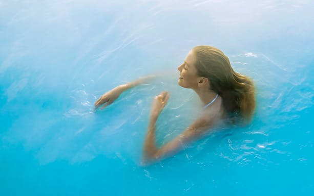 Person relaxing in the Blue Lagoon's geothermal waters near Reykjavik.