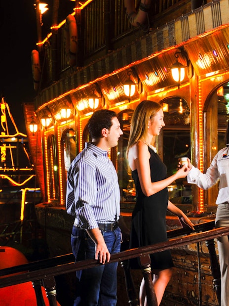 Guests enjoying a Dhow Dinner Cruise on Dubai Creek at night.