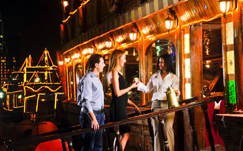 Guests enjoying a Dhow Dinner Cruise on Dubai Creek at night.