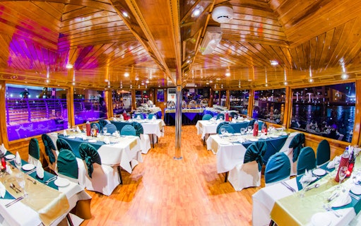 Dhow dinner cruise interior with set tables on Dubai Creek.