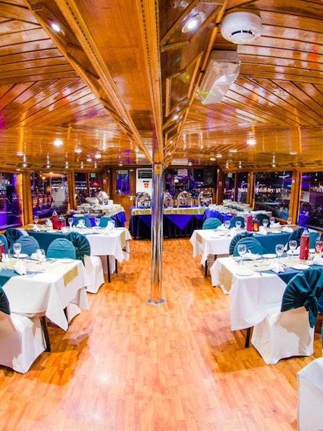 Dhow dinner cruise interior with set tables on Dubai Creek.