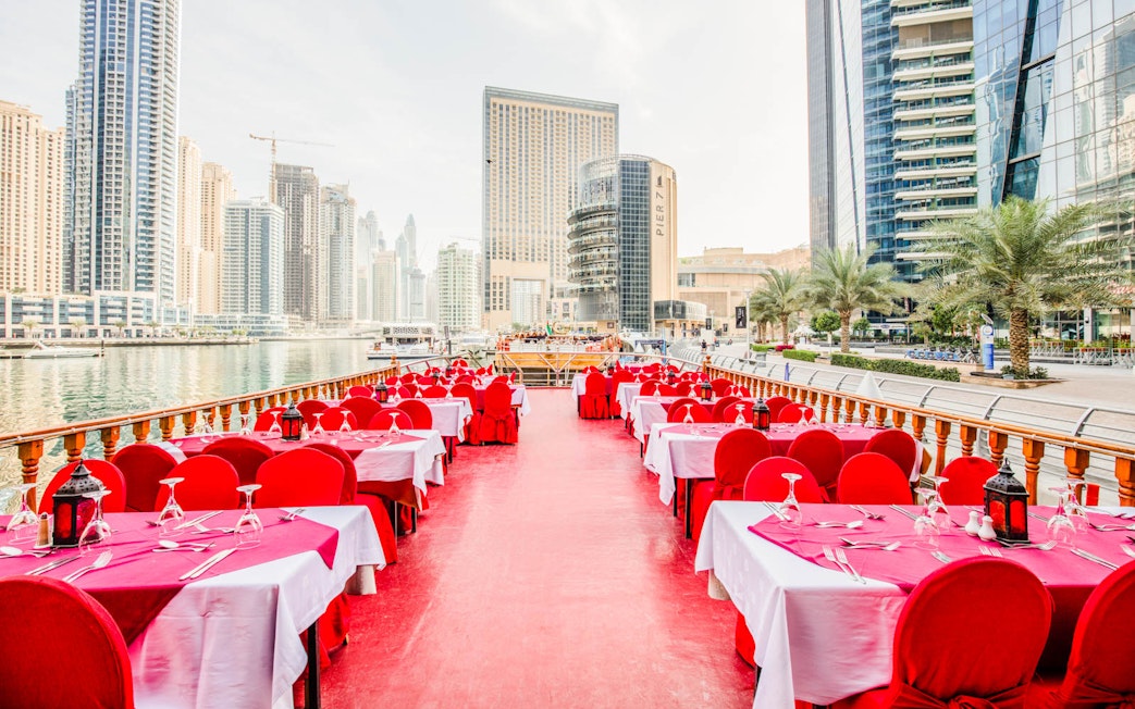 Dhow cruise dining setup on Dubai Creek with city skyline in the background.