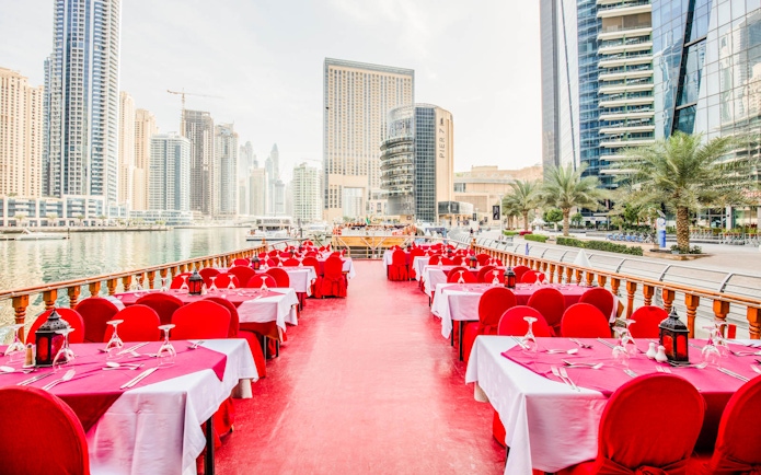 Dhow cruise dining setup on Dubai Creek with city skyline in the background.