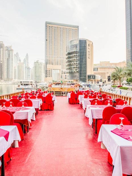 Dhow cruise dining setup on Dubai Creek with city skyline in the background.