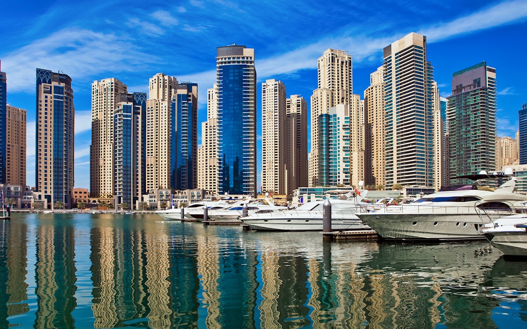 Yachts docked at Dubai Marina with skyscrapers in the background.