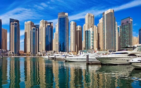 Yachts docked at Dubai Marina with skyscrapers in the background.