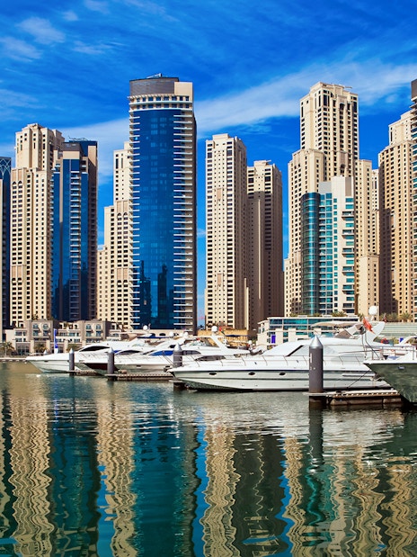 Yachts docked at Dubai Marina with skyscrapers in the background.