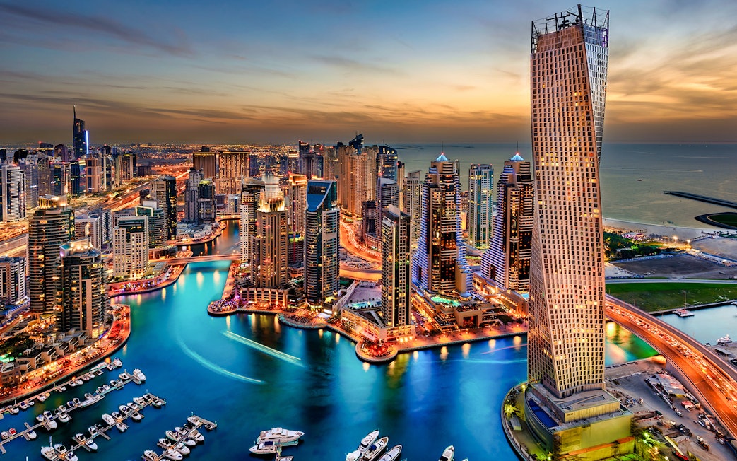 Dubai Marina skyline at sunset, view of skyscrapers and waterway.