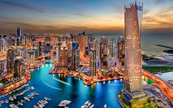 Dubai Marina skyline at sunset, view of skyscrapers and waterway.