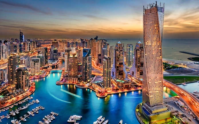 Dubai Marina skyline at sunset, view of skyscrapers and waterway.