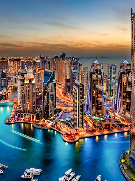 Dubai Marina skyline at sunset, view of skyscrapers and waterway.