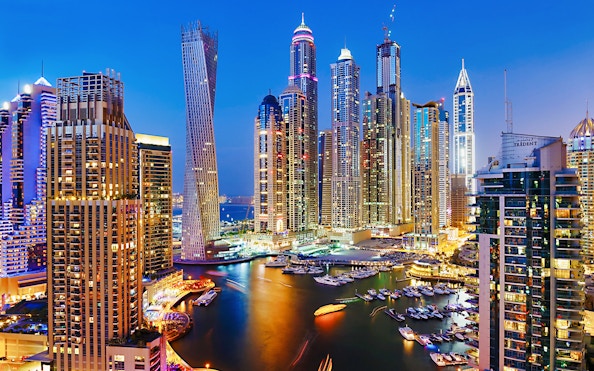 Dubai Marina skyline at night with illuminated skyscrapers and yachts, Combo: Dhow Cruise + Desert Safari.