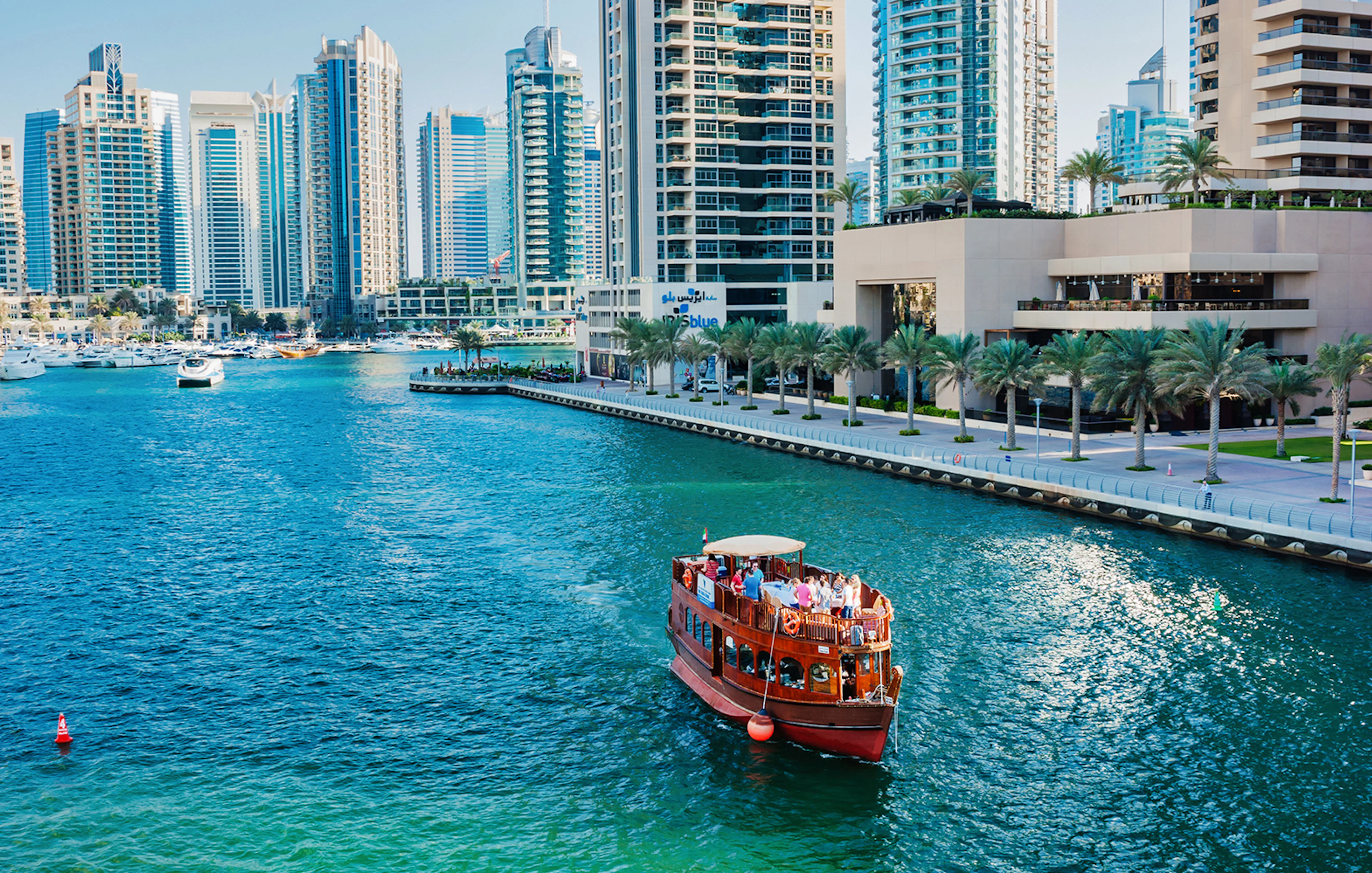 Dhow boat cruising in Dubai Marina with skyscrapers in the background.