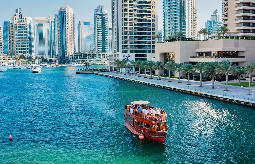 Dhow boat cruising in Dubai Marina with skyscrapers in the background.