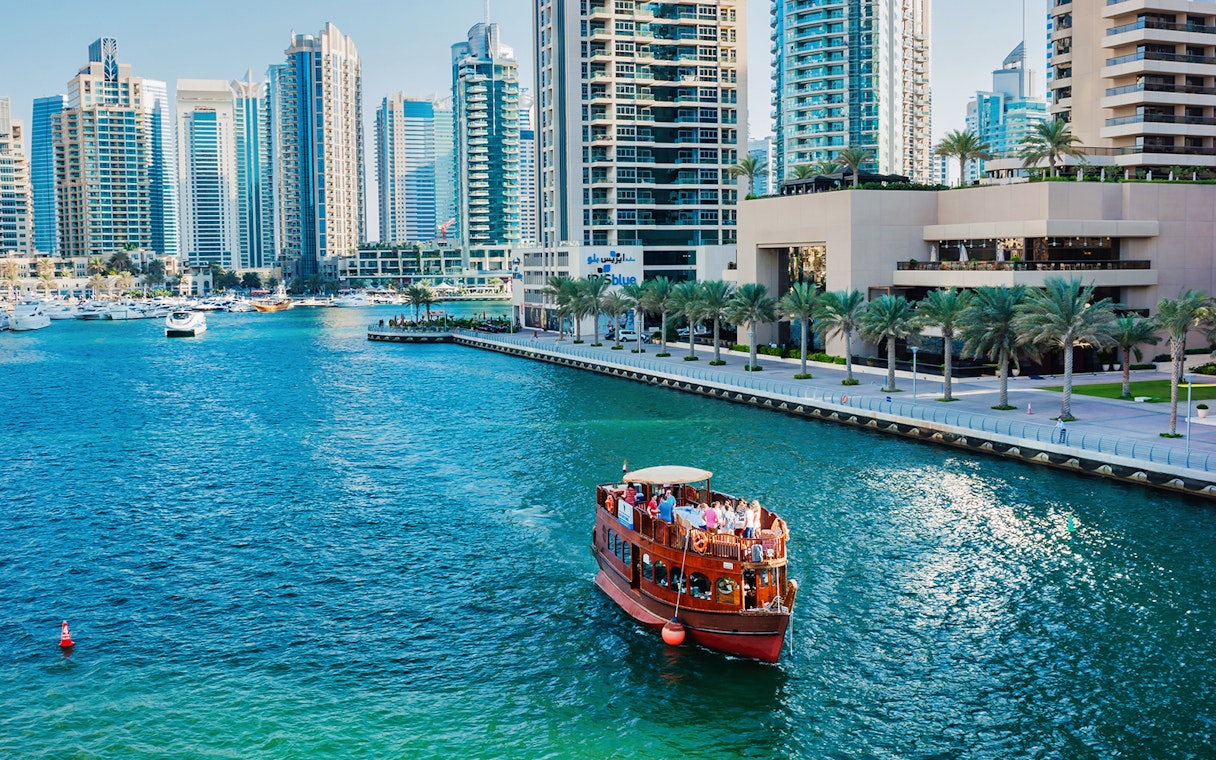 Dhow boat cruising in Dubai Marina with skyscrapers in the background.