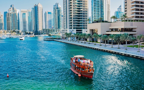 Dhow boat cruising in Dubai Marina with skyscrapers in the background.