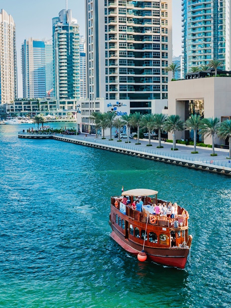 Dhow boat cruising in Dubai Marina with skyscrapers in the background.