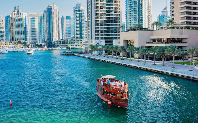 Dhow boat cruising in Dubai Marina with skyscrapers in the background.