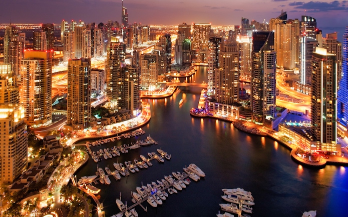 Dubai Marina skyline at night with illuminated skyscrapers and yachts, part of Dhow Cruise + Desert Safari combo.