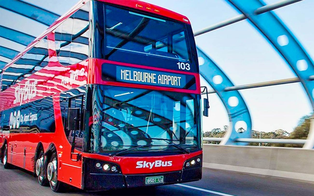 Skybus shuttle driving to Melbourne Airport on a highway bridge.
