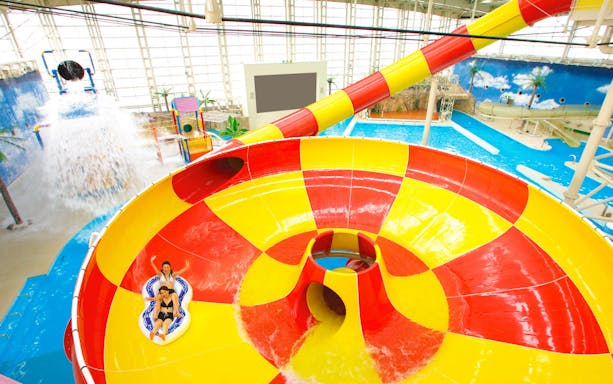 Visitors enjoying a colorful water slide at Spa World Osaka.