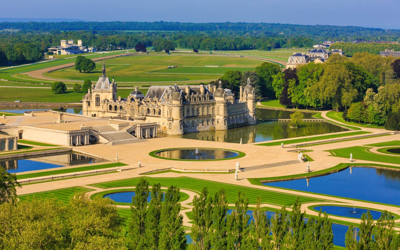Chateau of Chantilly with gardens and reflecting pools, France.