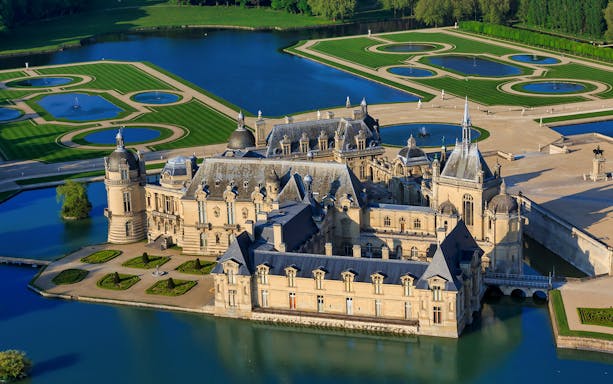 Chateau of Chantilly surrounded by gardens and water features in France.