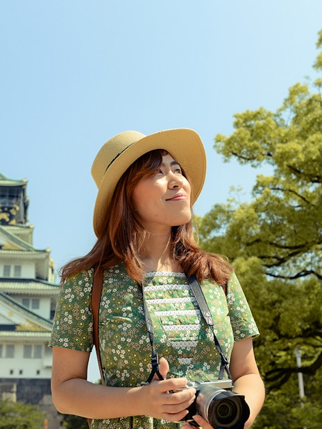 Tourist with camera in front of Osaka Castle, Japan, using Osaka Amazing Pass.