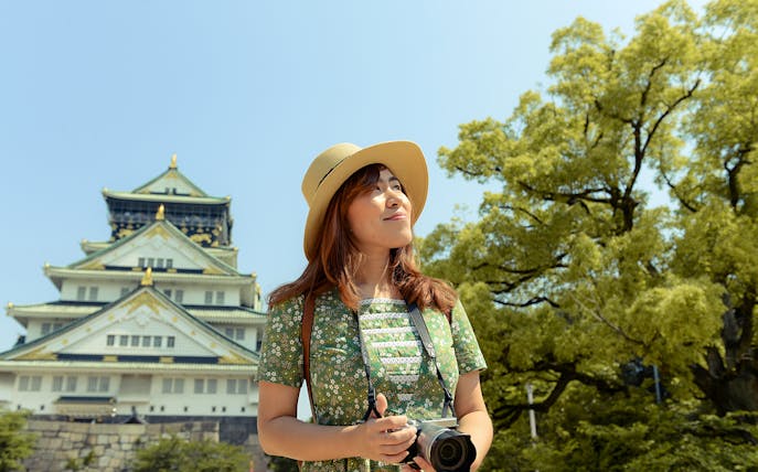 Tourist with camera in front of Osaka Castle, Japan, using Osaka Amazing Pass.