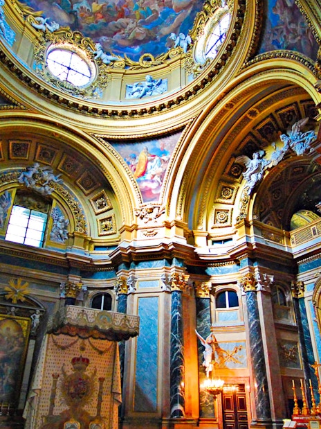 Royal Palace interior with ornate ceiling and columns, featuring detailed frescoes and gold accents.