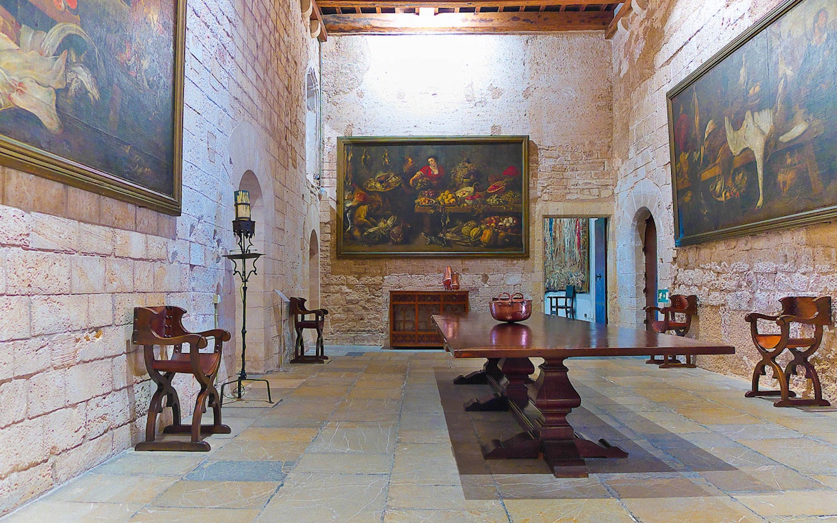 Royal Palace of La Almudaina interior with historic paintings and wooden furniture.