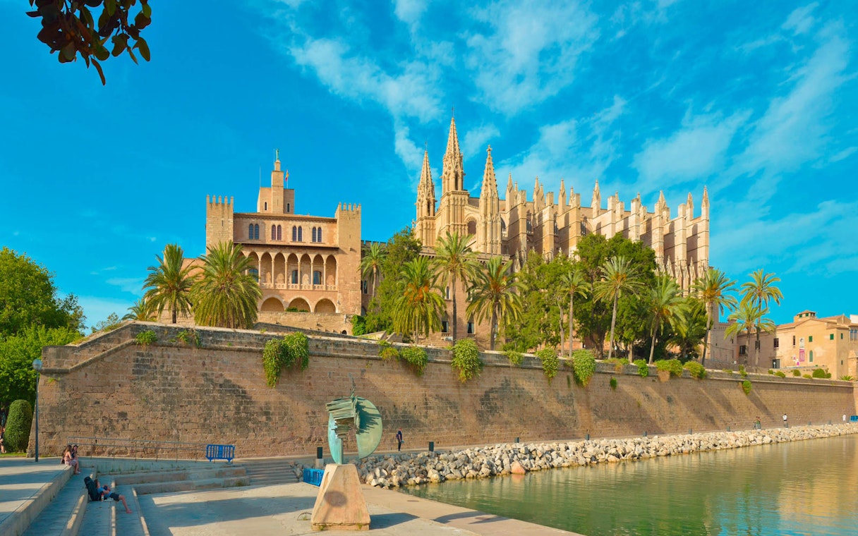 Royal Palace of La Almudaina with palm trees and waterfront in Palma, Mallorca.