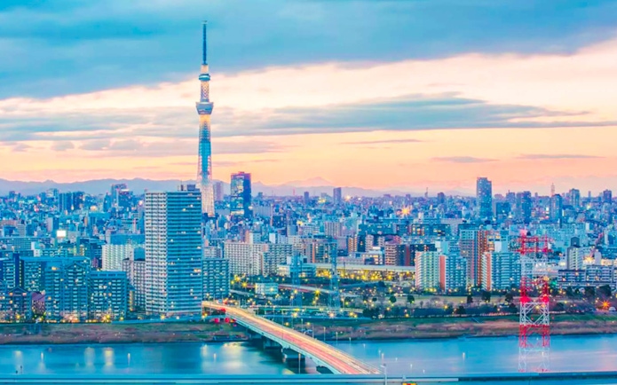 Tokyo Skytree towering over cityscape at sunset, view from river.