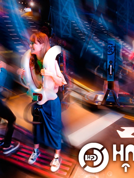 Visitors enjoying a ride at Tokyo JOYPOLIS Halfpipe attraction.