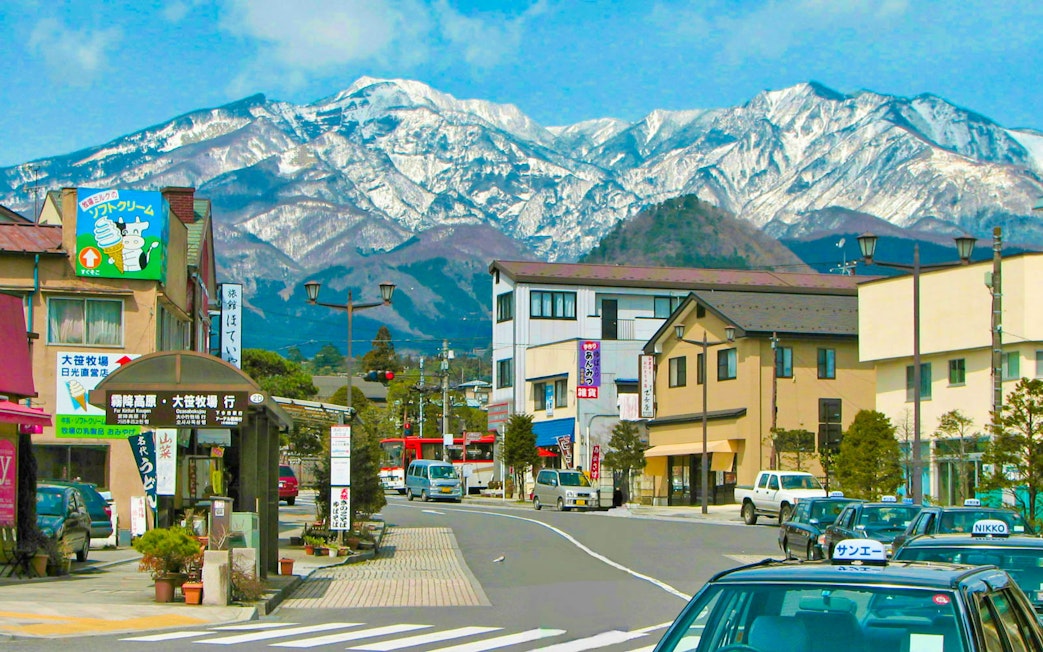 Street view in Nikko, Japan with snow-capped mountains in the background.