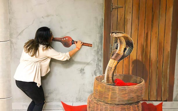 Person interacting with 3D snake illusion at 3D World Dubai Trick-Art ‘Selfie’ Museum.