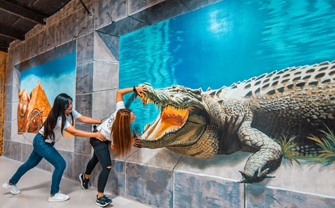 Visitors interacting with crocodile illusion at 3D World Dubai Trick-Art Museum.
