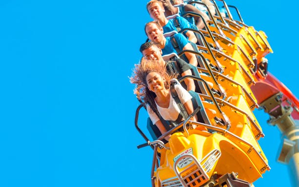 People enjoying a roller coaster ride in San Francisco with clear blue sky.