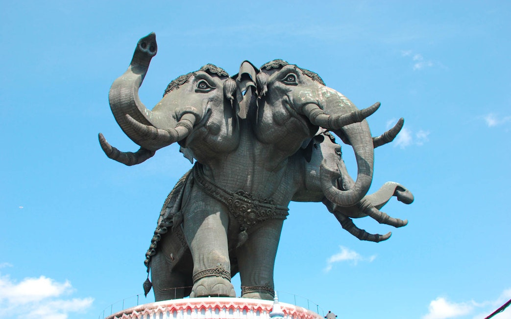Three-headed elephant statue at Erawan Museum, Bangkok, under a clear sky.