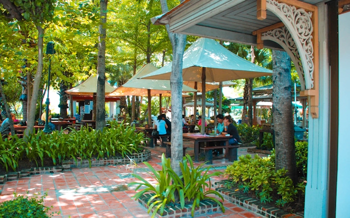 Outdoor seating area at Erawan Museum with visitors under shaded canopies.