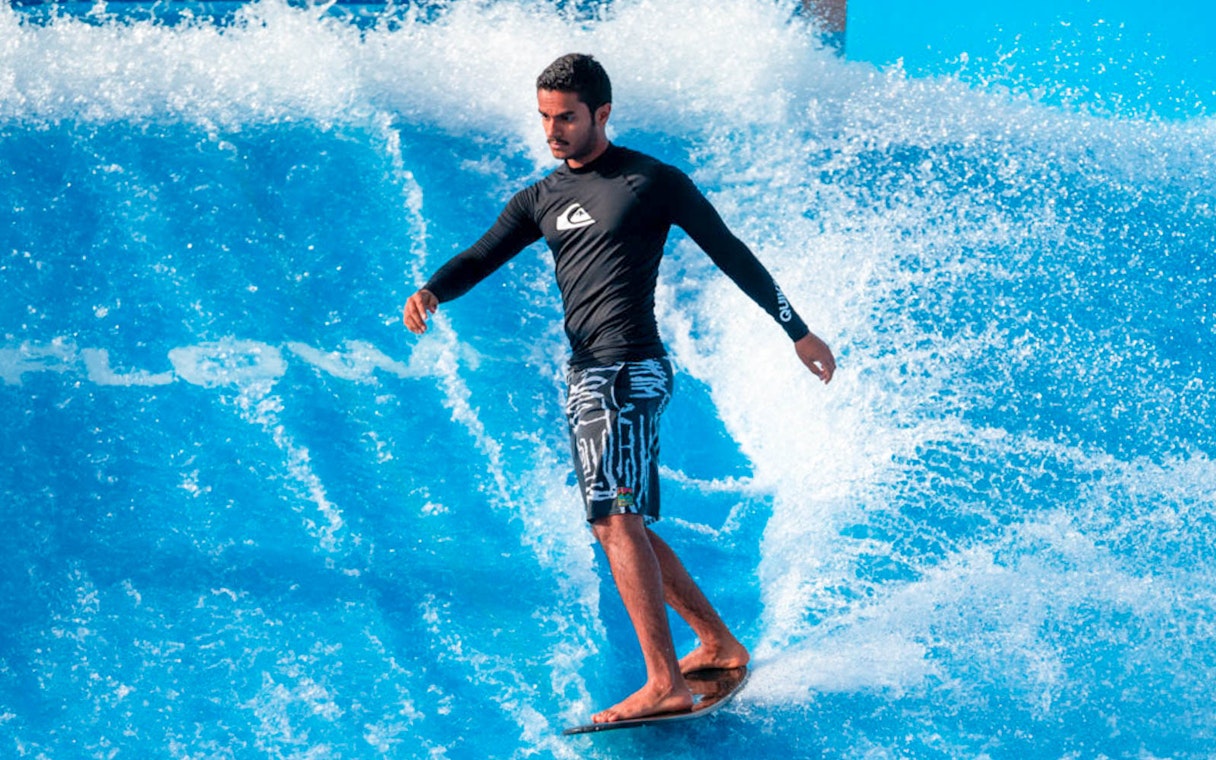Surfer balancing on artificial wave at Flow House Bangkok.