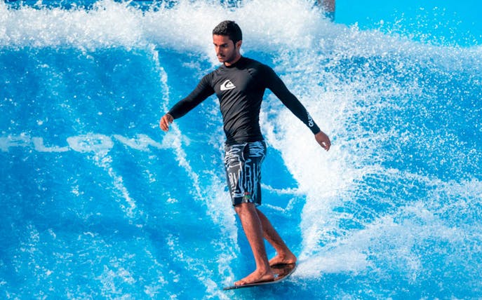 Surfer balancing on artificial wave at Flow House Bangkok.