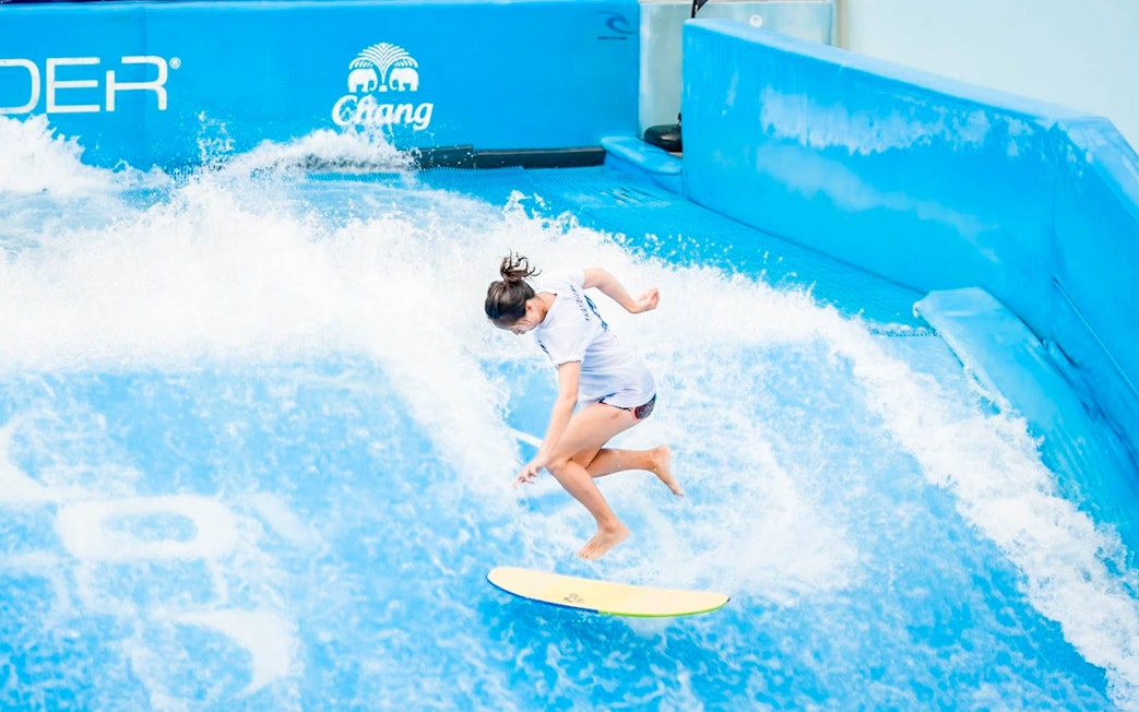 Surfer catching a wave at Flow House Bangkok indoor surf experience.