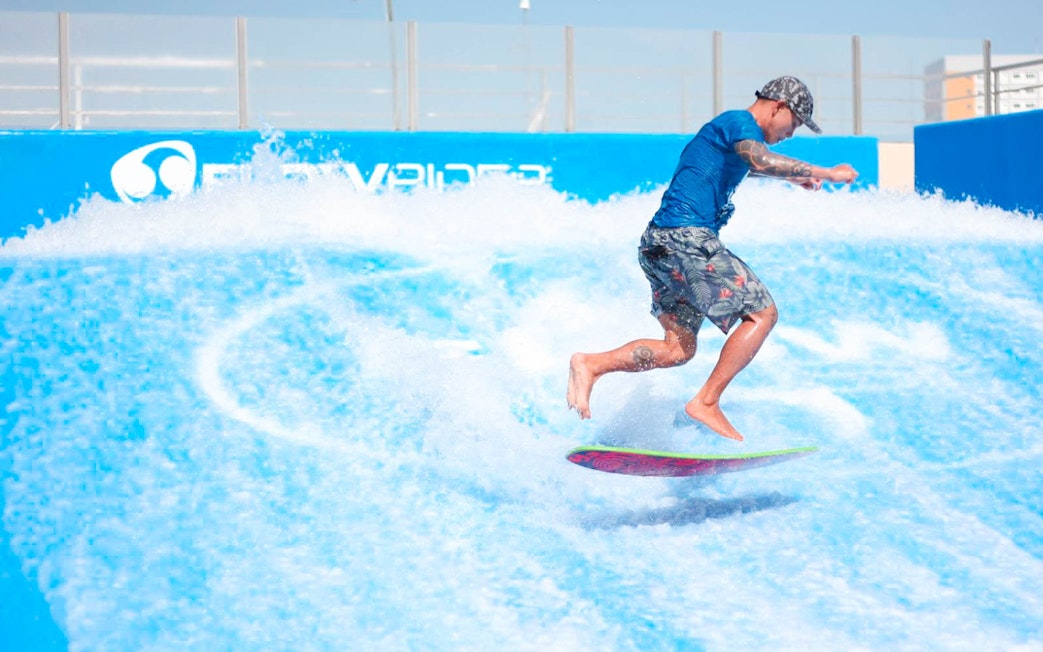 Surfer riding artificial wave at Flow House Bangkok.